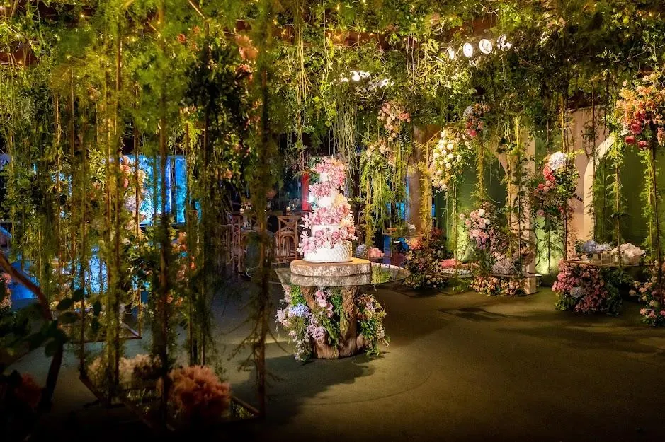 Jardim de folhagens e flores com mesa de bolo ao fundo