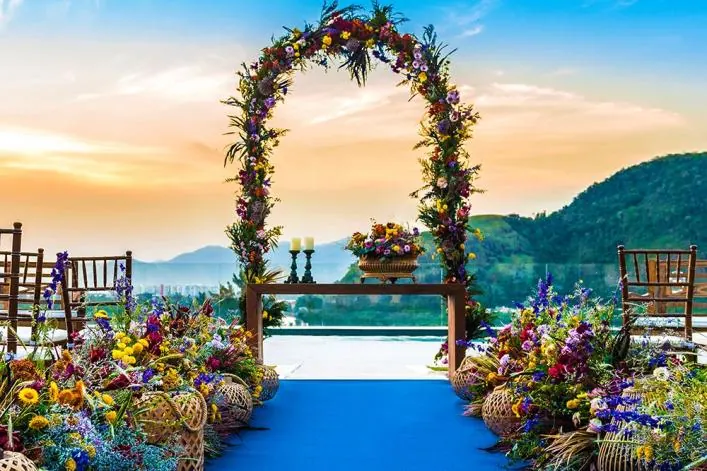 Arco de flores do campo sobre tapete azul ao pôr do sol