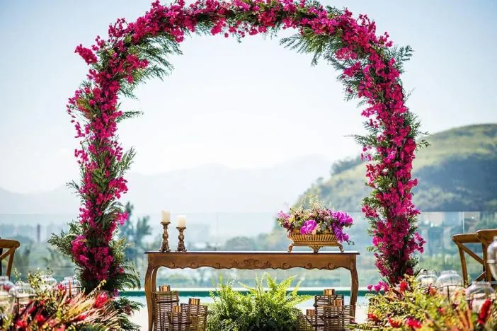 Arco de buganvília rosa sobre mesa de madeira com vista para as montanhas