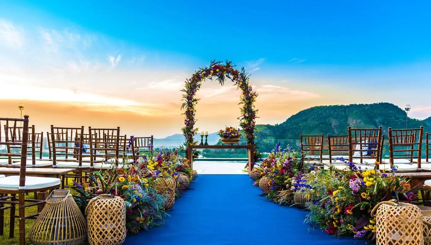 Foto real da cerimônia com arco de flores do campo e tapete azul